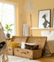 Sypialnia z ł&oacute;żkiem małżeńskim, wiszącym fotelem i ścianami w ciepłym odcieniu ż&oacute;łto-pomarańczowym.