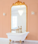 Łazienka z wolnostojącą wanną i lustrem w złotej ramie, ściany w kolorze brzoskwiniowym S1015-Y90R.