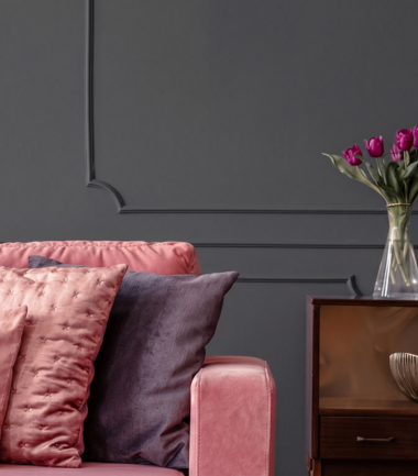 Elegancki salon z tapicerowaną sofą w różowym kolorze i ścianą w kolorze B22 Czarny Diament.