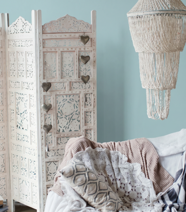 przytulny salon z błękitną ścianą, parawanem w stylu boho i boho abażurem