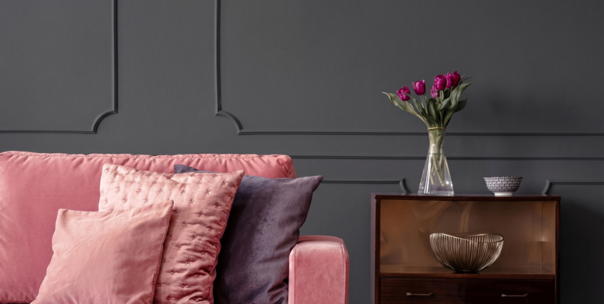 Elegancki salon z tapicerowaną sofą w różowym kolorze i ścianą w kolorze B22 Czarny Diament.