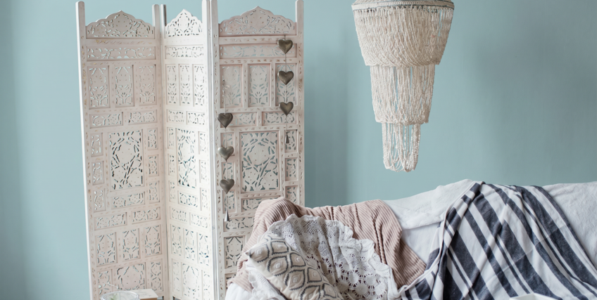 przytulny salon z błękitną ścianą, parawanem w stylu boho i boho abażurem