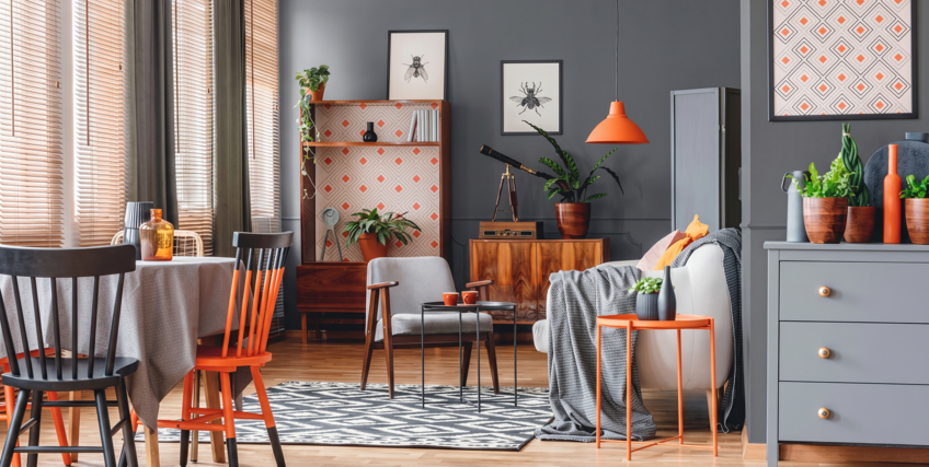Salon w stylu vintage z szarymi ścianami w kolorze RAL 7043 i akcentami pomarańczowymi