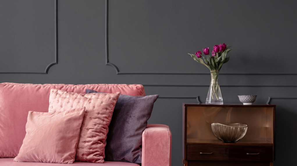 Elegancki salon z tapicerowaną sofą w r&oacute;żowym kolorze i ścianą w kolorze B22 Czarny Diament.