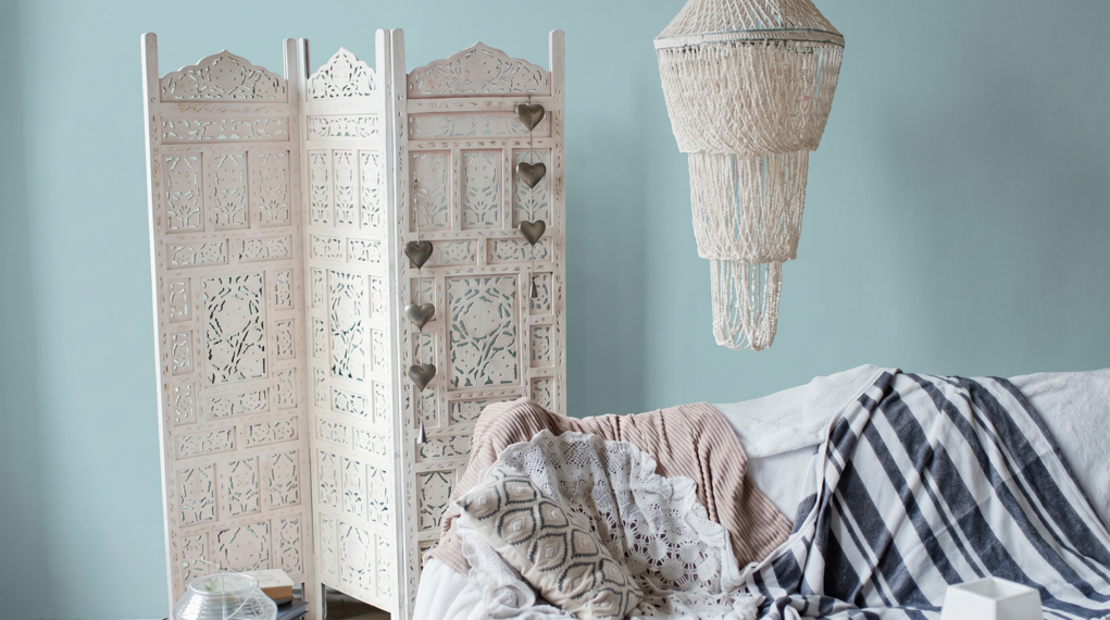 przytulny salon z błękitną ścianą, parawanem w stylu boho i boho abażurem