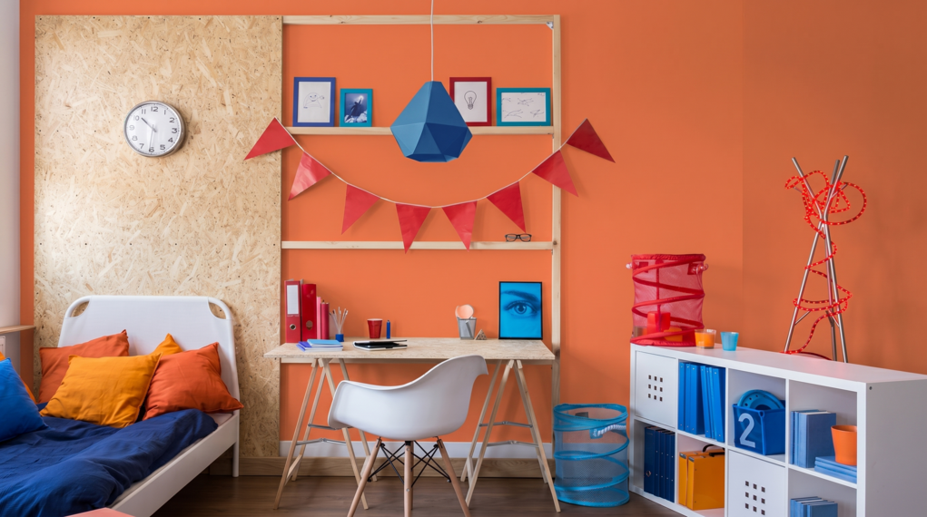 Pok&oacute;j nastolatka z pomarańczową ścianą w kolorze S0585-Y50R, biurkiem i ł&oacute;żkiem.